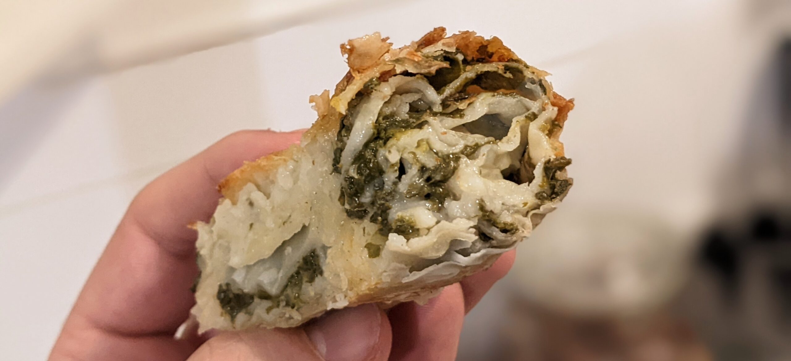 Cross section of cheese and spinach bourekas showing the spinach and melted cheese filling inside flaky pastry