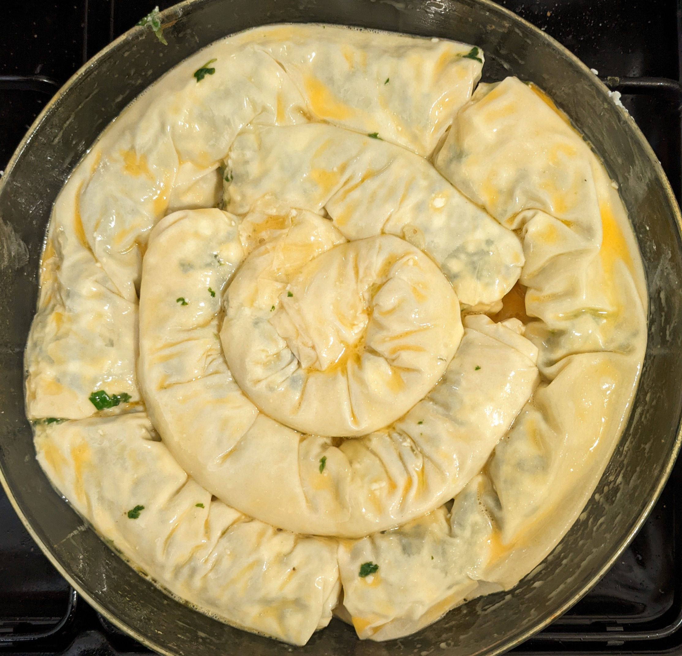 Unbaked cheese and spinach bourekas filo spiral with egg wash in a round pan