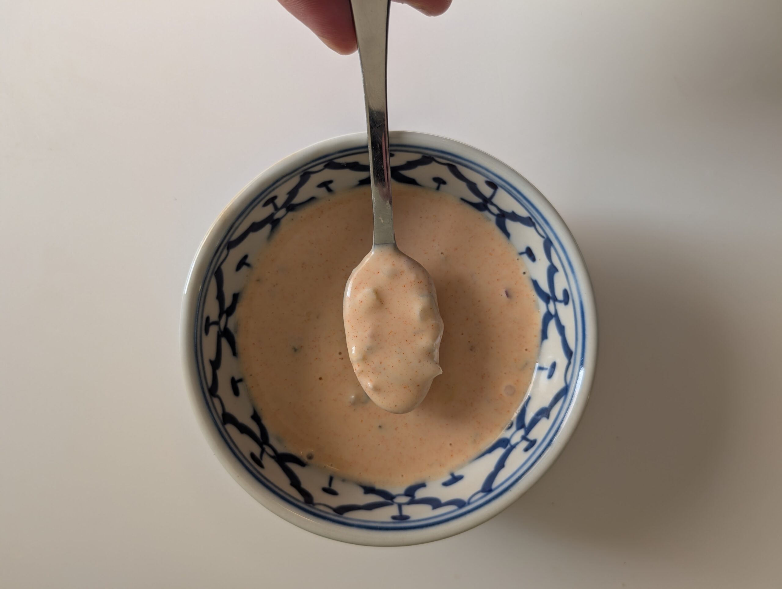 Homemade McDonald's sauce in a blue bowl with a spoon showing the creamy orange-pink texture
