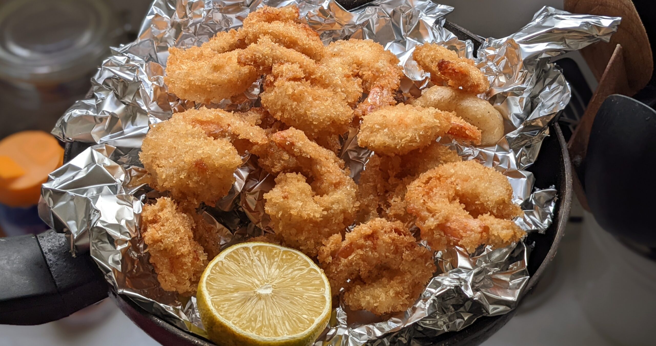 Crispy fried tofu fingers served in a foil pan with lemon wedges