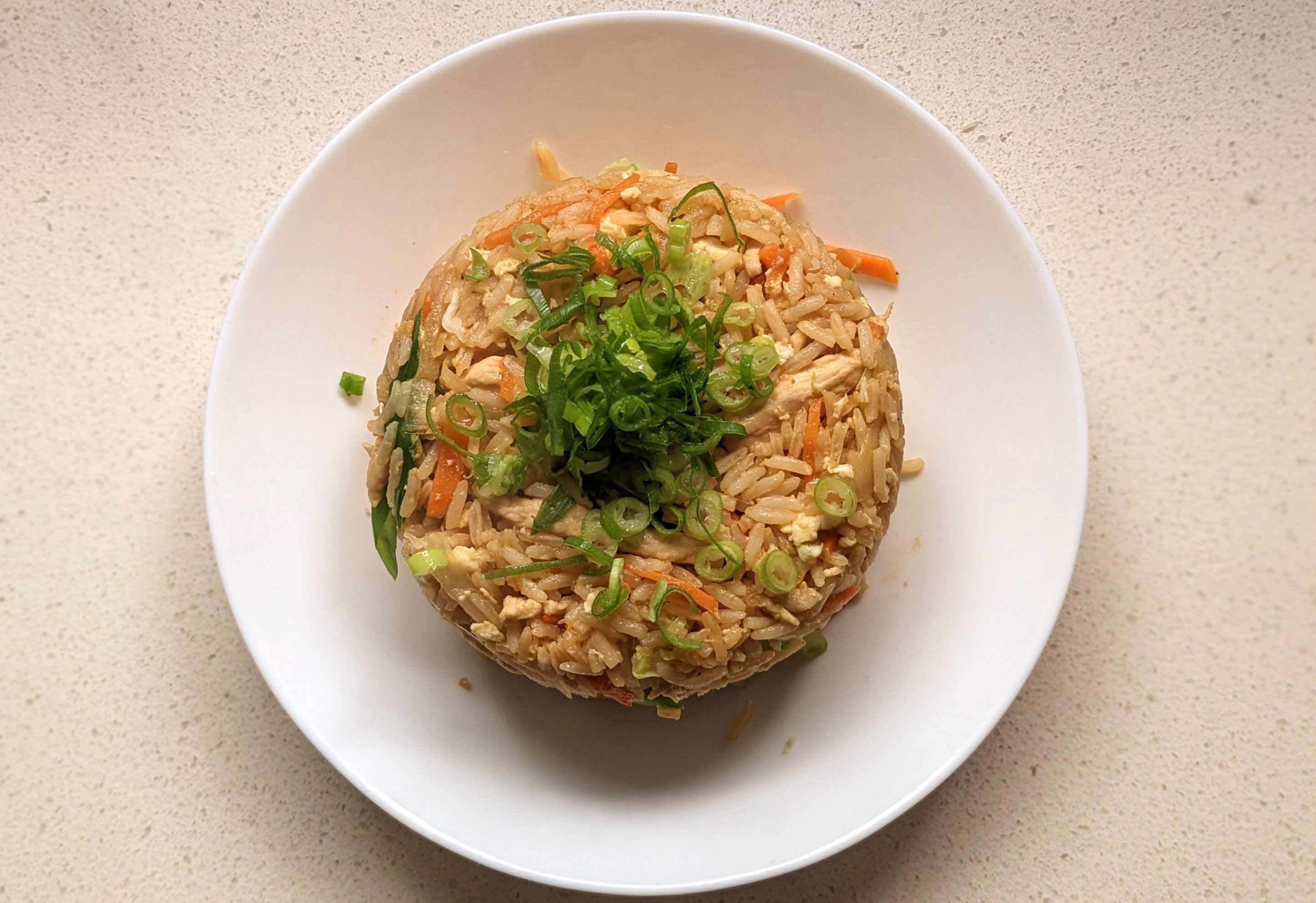Dad's fried rice overhead shot in a white bowl with green onion garnish