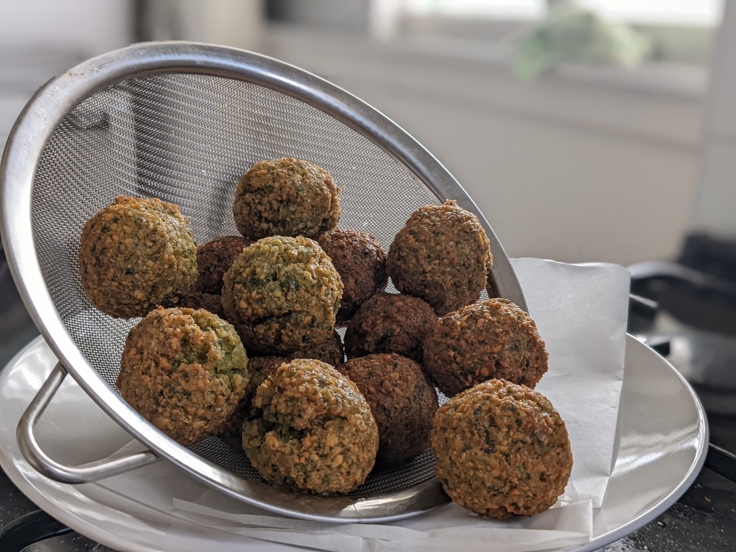 Crispy homemade falafel balls fresh from the fryer in a metal strainer