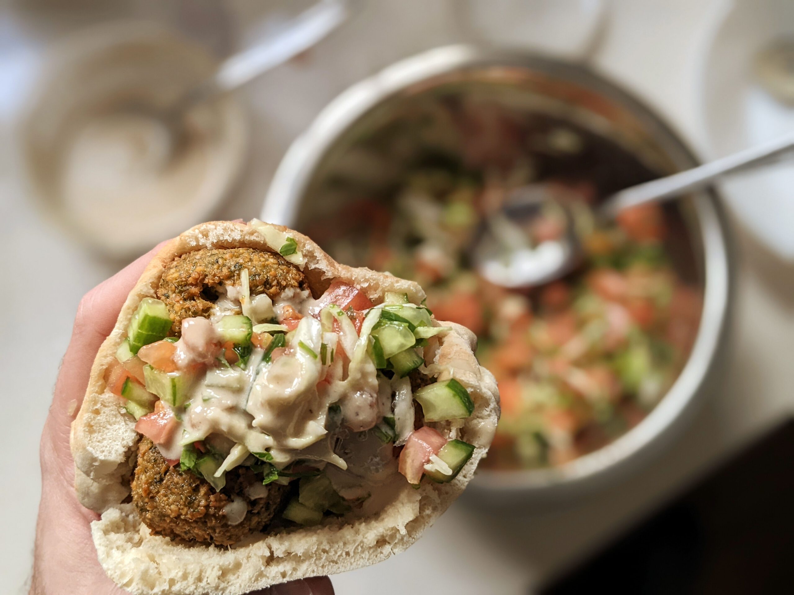 Homemade falafel recipe stuffed in a pita with tahini, fresh salad and vegetables