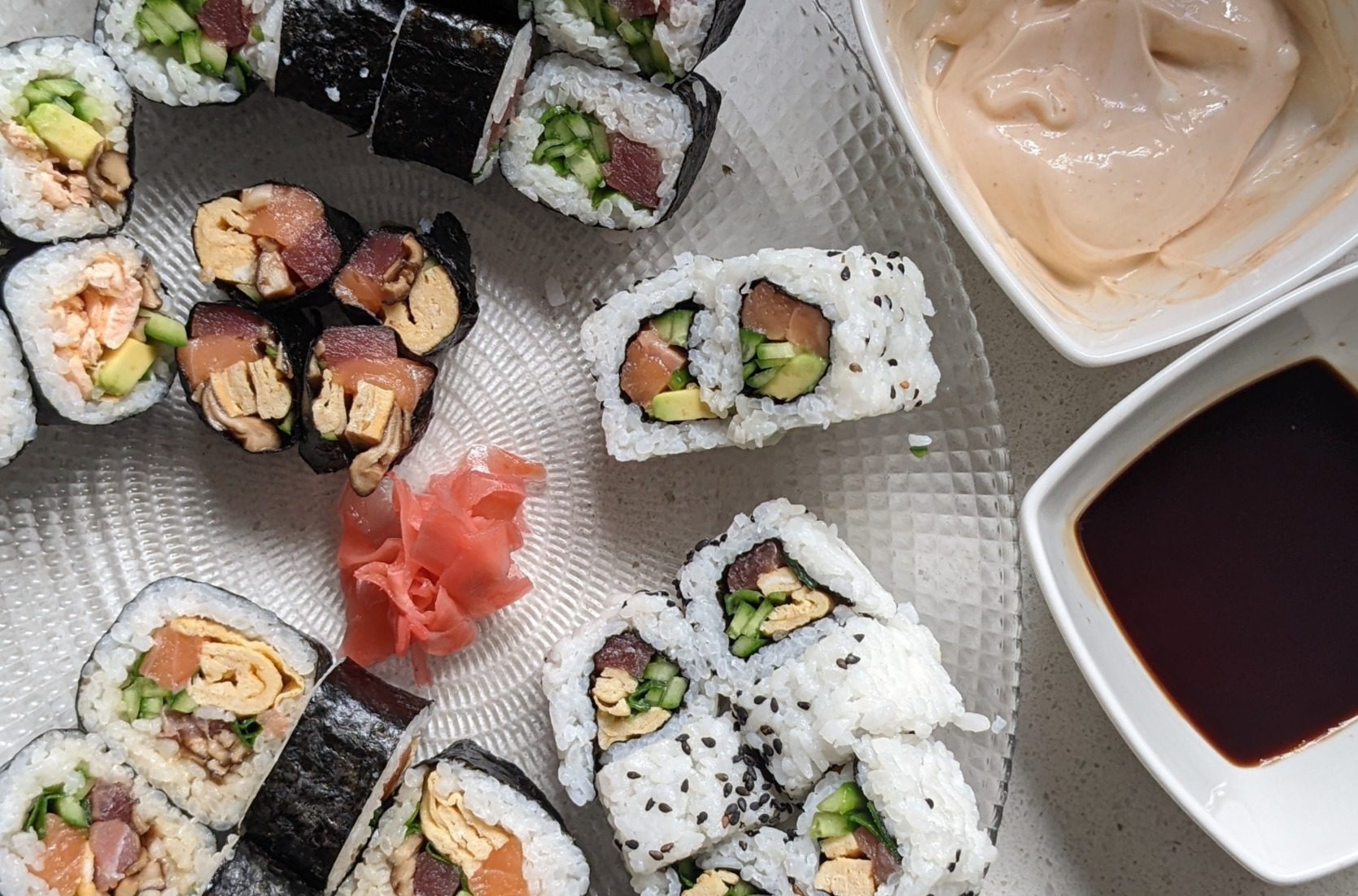Homemade sushi rolls on a plate with soy sauce and pickled ginger
