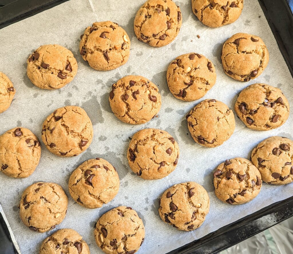 Peanut butter chocolate chip cookies on a parchment-lined baking tray, overhead view