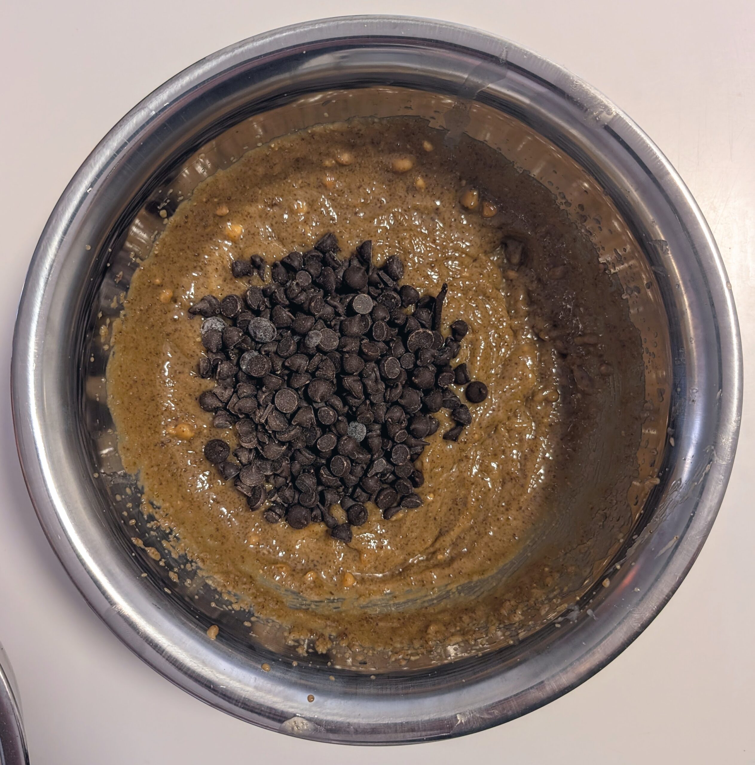 Wet peanut butter cookie dough in a mixing bowl with chocolate chips folded in