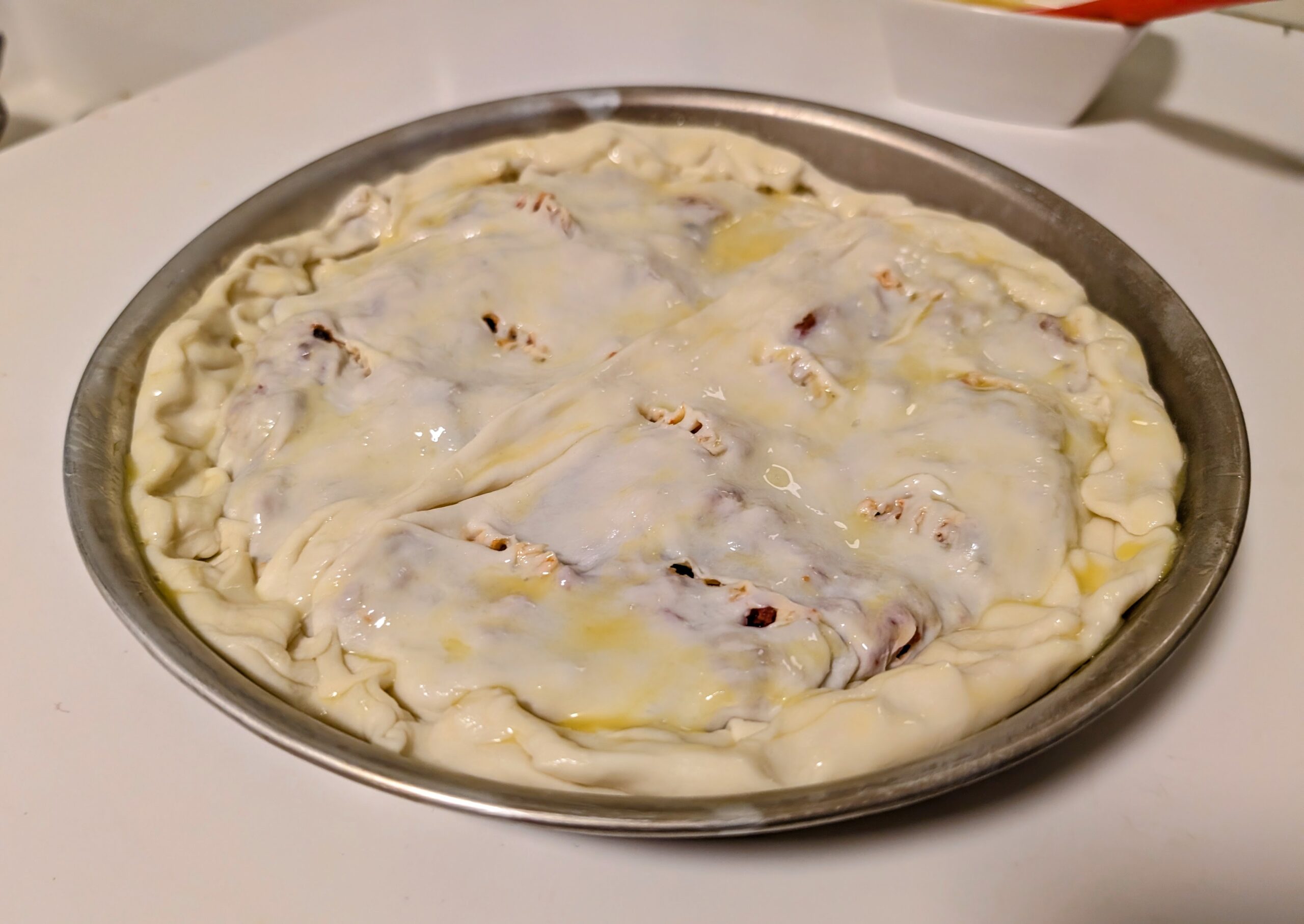 Assembled puff pastry meatloaf with egg wash brushed over the top before baking