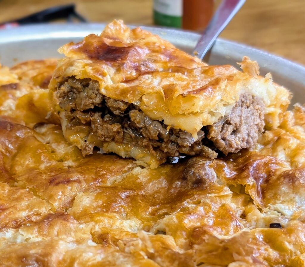 Puff pastry meatloaf recipe slice being lifted showing juicy beef filling inside a golden crispy crust