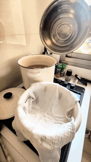 Animated GIF of a cheesecloth-lined strainer being set up over a clean pot, ready to strain the chicken bone broth
