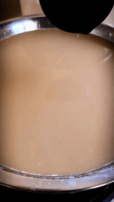 Animated GIF of the surface of freshly strained golden chicken bone broth in a large pot