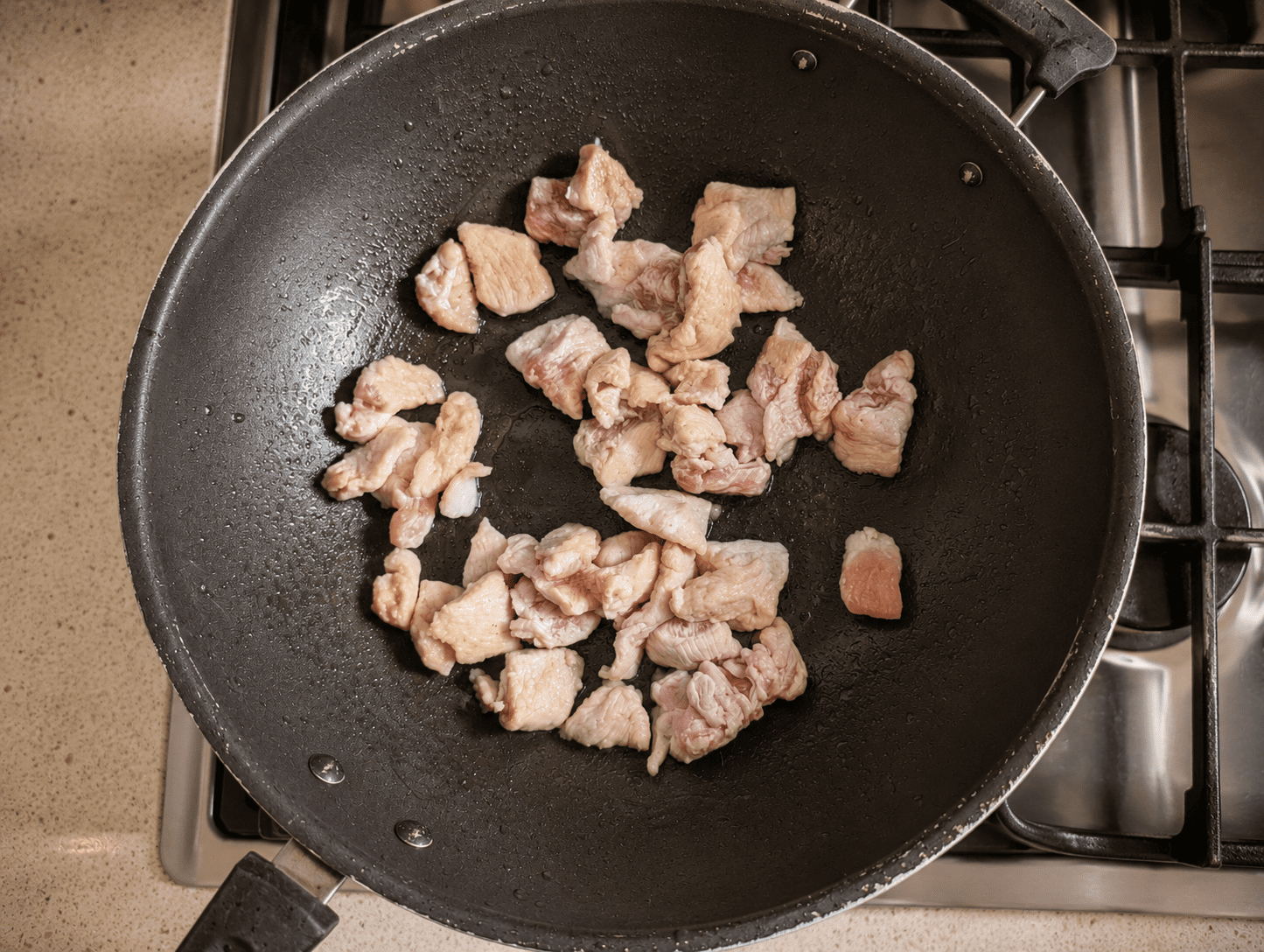 Thinly sliced raw chicken pieces coated in corn flour, frying in a hot wok