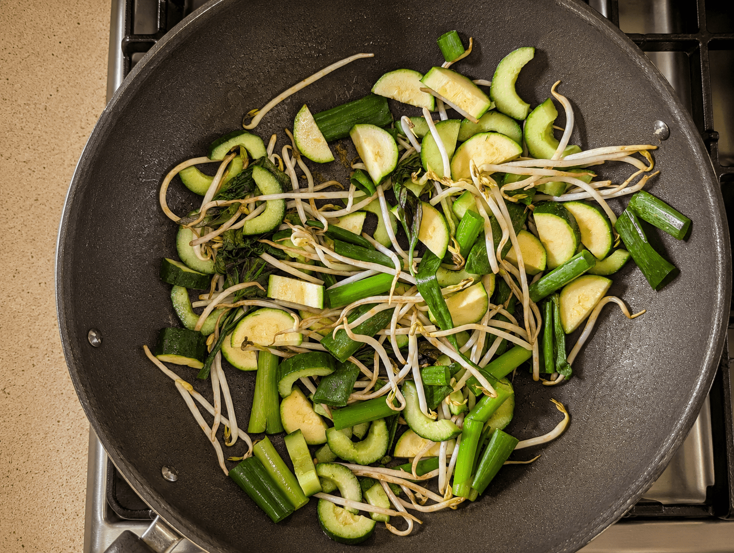 Zucchini, cucumber, bean sprouts and basil stir-frying in a hot wok