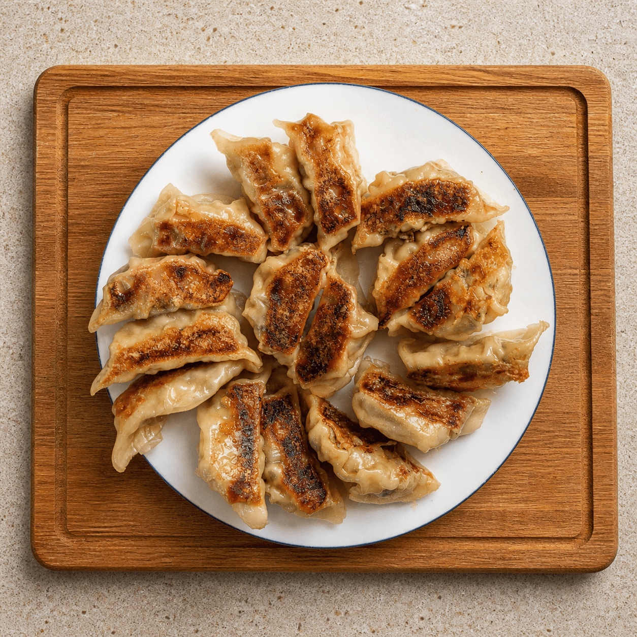 Overhead view of pan-fried gyoza on a white plate showing the golden brown crispy bottoms