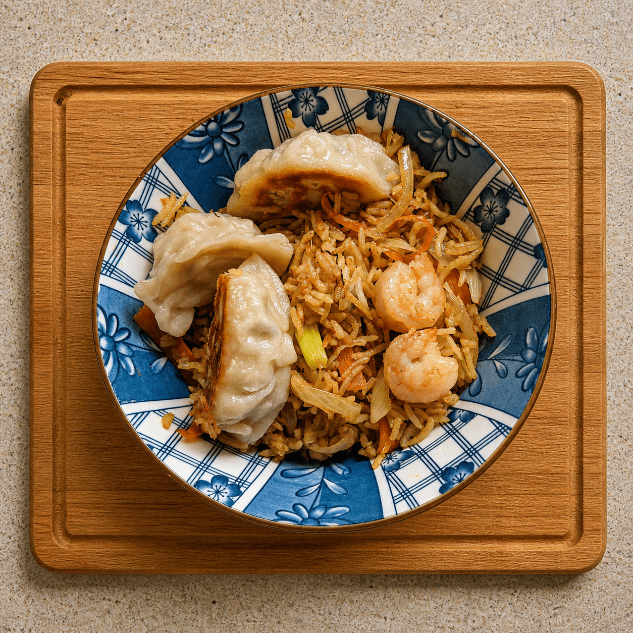 Japanese gyoza served on top of fried rice with shrimp in a blue and white bowl
