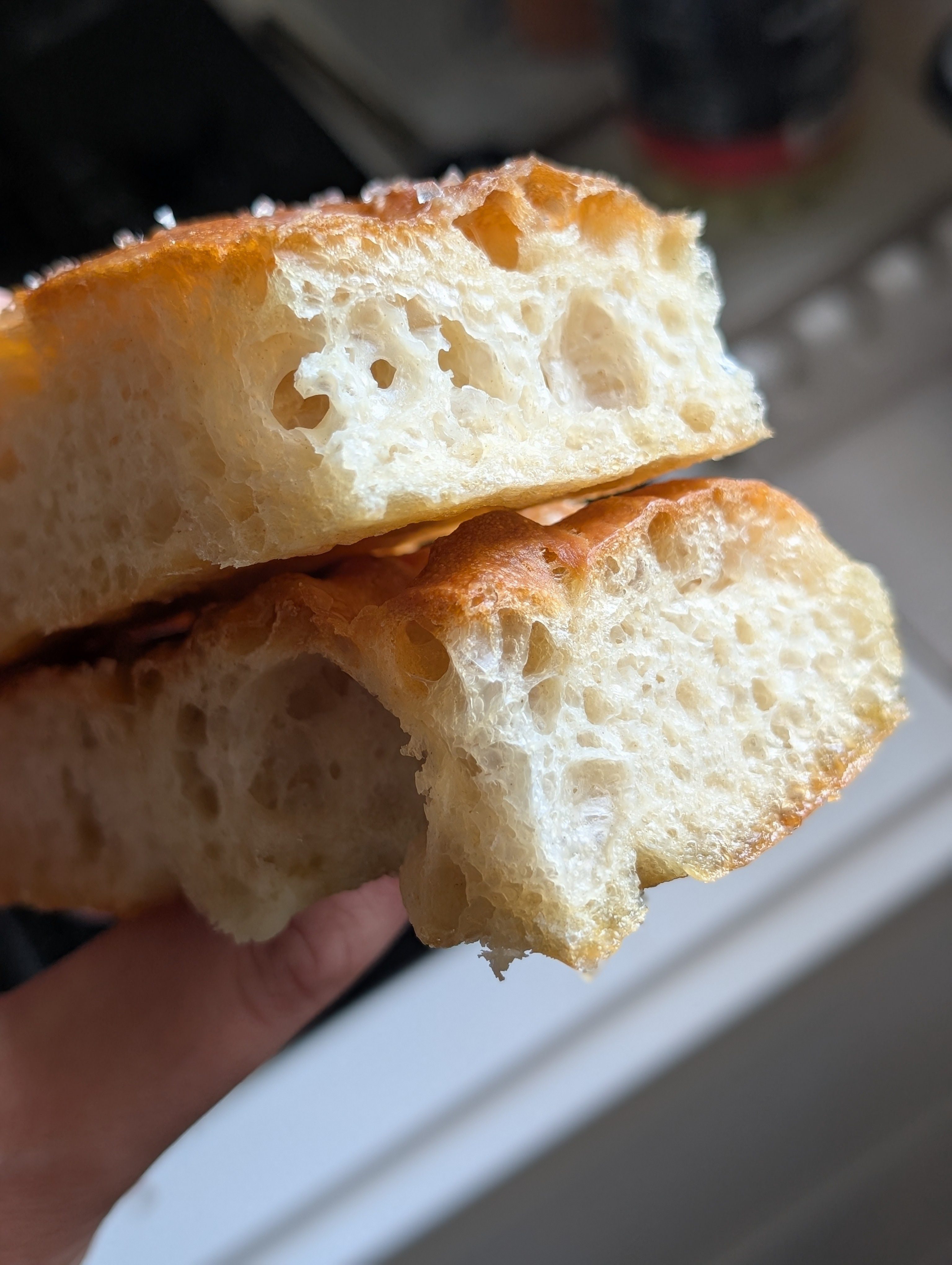 Close-up crumb shot of no knead focaccia showing large open holes, translucent gluten strands and a golden crust