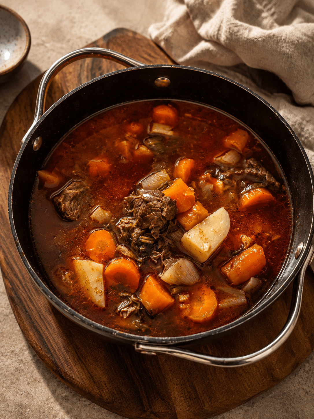 Slow cooked beef goulash in the pot with soft carrots, potato and tender beef in a deep red broth