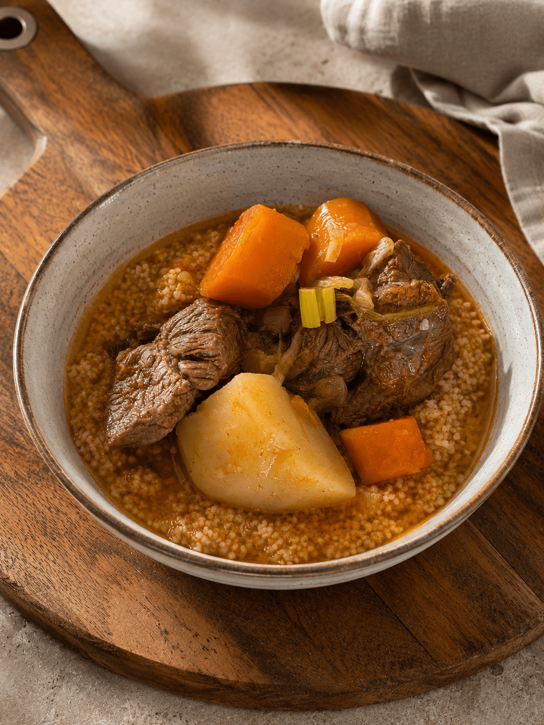 Beef goulash served over couscous in a bowl with soft potato, carrot and tender beef