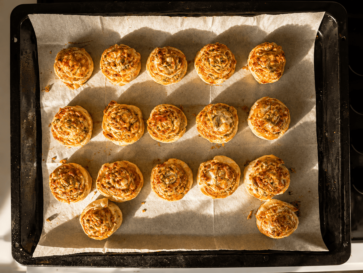 Golden baked puff pastry pizza rolls on a parchment lined baking tray