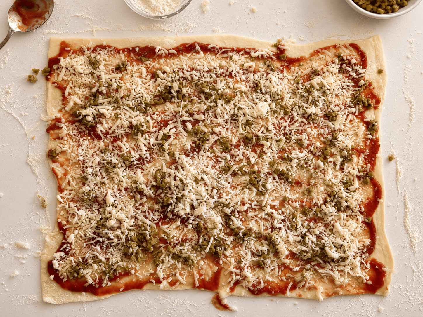 Puff pastry topped with tomato sauce, chopped green olives and a layer of shredded cheese