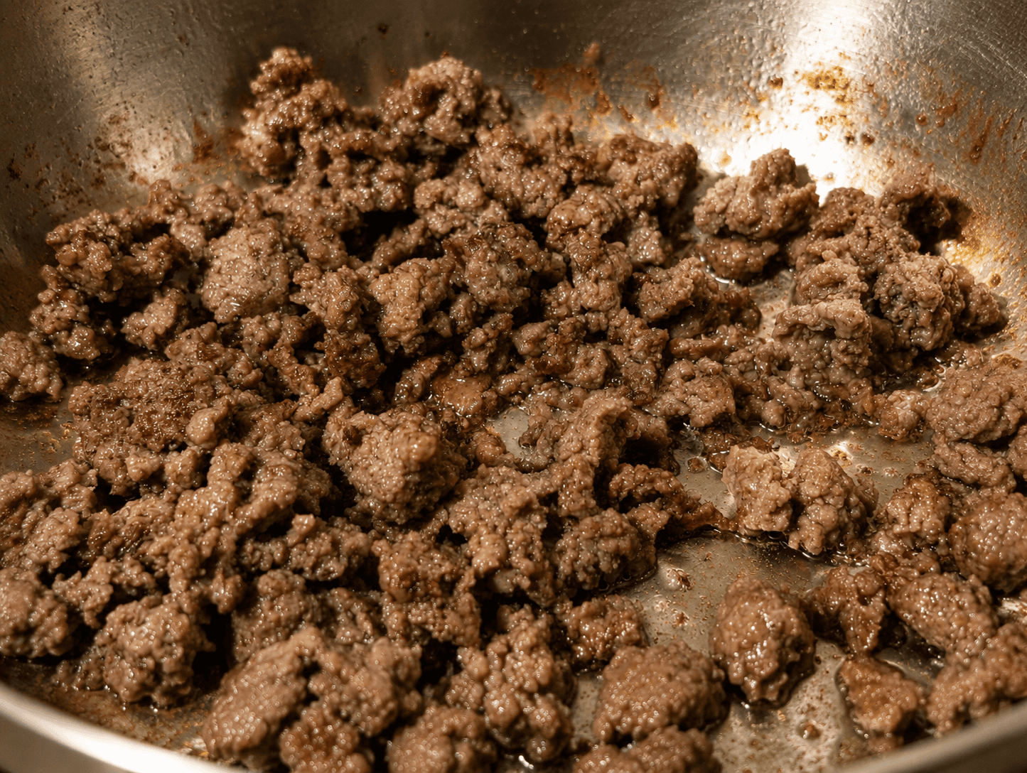 Ground beef fried until deeply browned and crispy in a stainless steel pan