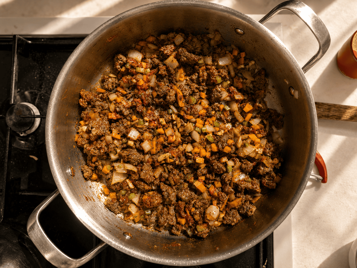 Ground beef, sautéed vegetables, and tomato paste cooked down together in a pan, deeply colored and combined