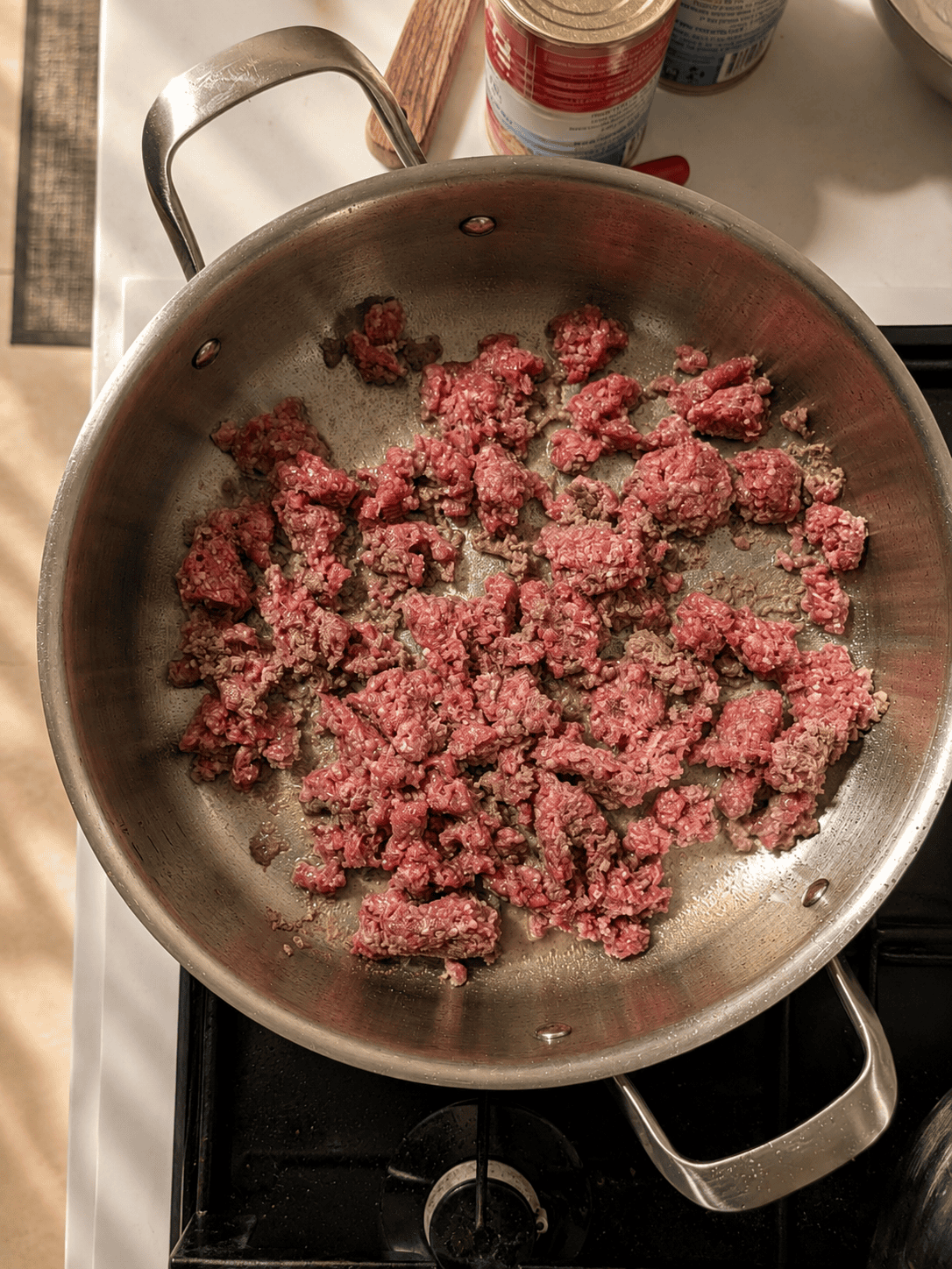 Raw ground beef mixed with baking soda resting in a stainless steel pan before browning