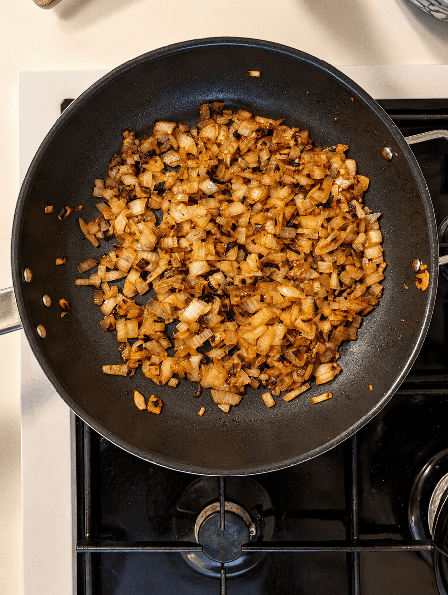 Finely diced white onions fried to deep golden brown with dark caramelized edges in a black pan